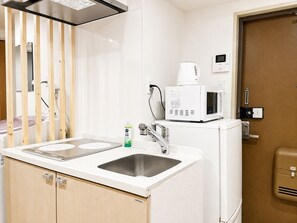 Una kitchenette compacta equipada con microondas, cafetera y pileta.