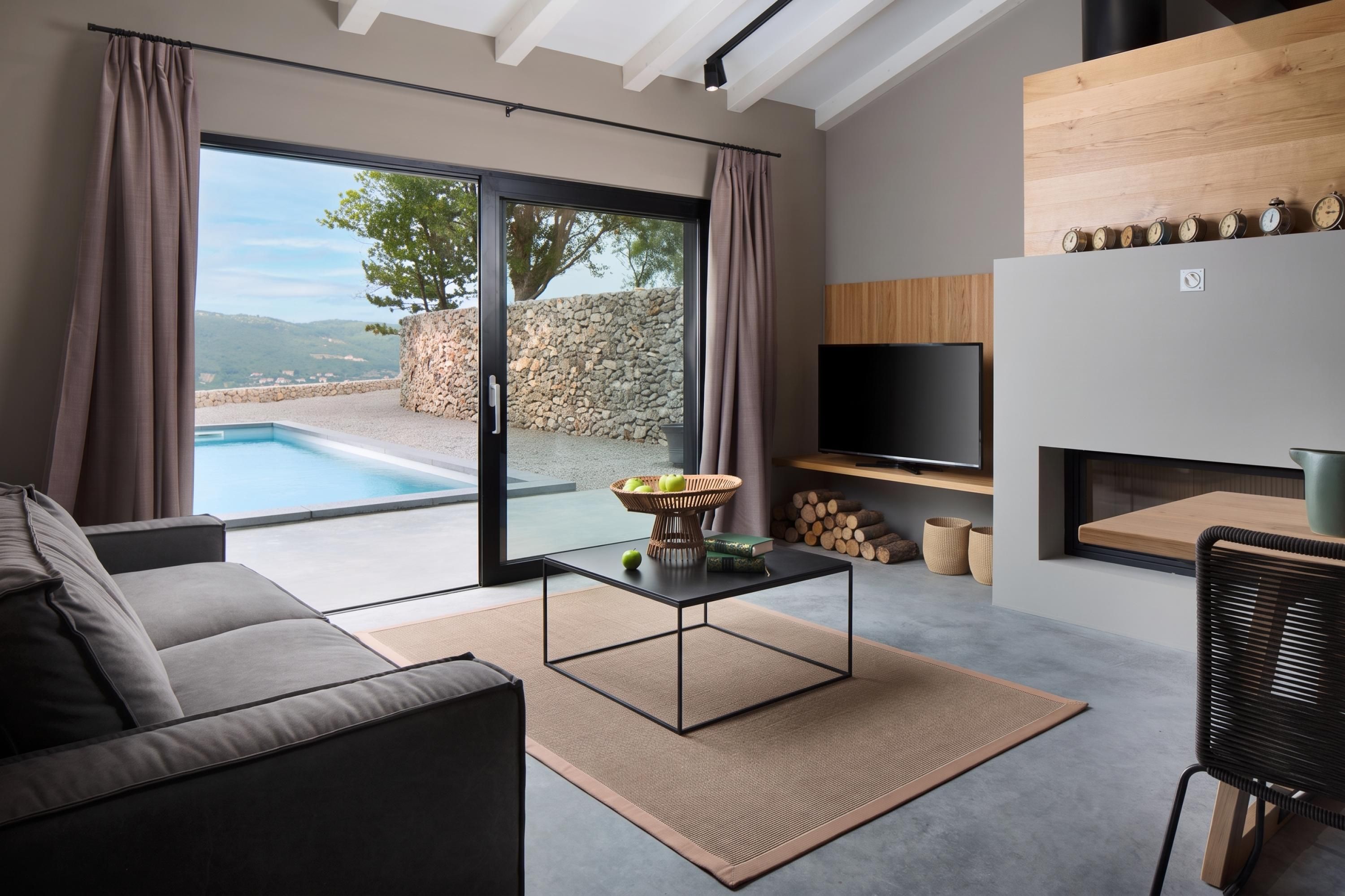 A modern living room with a pool view, a sofa, a coffee table, and a TV.