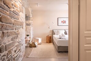 A bedroom with a stone wall, a bed with white bedding, a small bedside table, a lamp, and a framed picture on the wall. - Villa Baracchi – 4 BDR Pool Villa with Sauna in Kršan, Čepić, Croatia (Čepić)