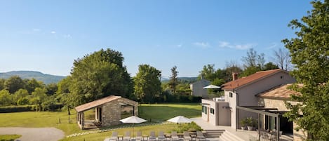 Una casa moderna con piscina, mobiliario de exterior y jardín.