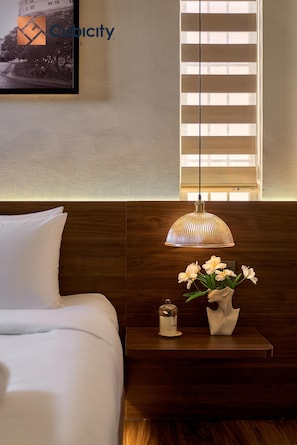 A hotel room with a bed, a nightstand with a lamp, and a window with blinds. - Cubicity Ba Huyen Thanh Quan (Ho Chi Minh City)