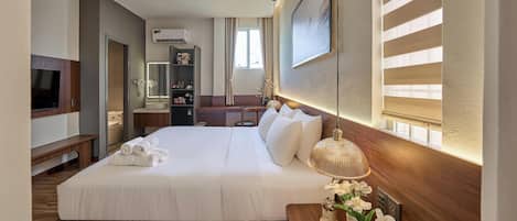 Una habitación de hotel con una cama grande, un escritorio, un tocador con espejo y una televisión.