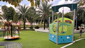 A playground with a circular swing set, a climbing structure, and a bench.