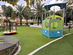 A playground with a circular swing set, a climbing structure, and a bench.