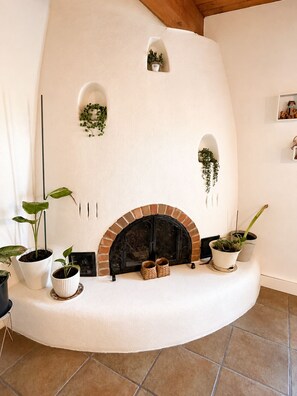 A curved fireplace with a brick arch, surrounded by potted plants and a woven basket.