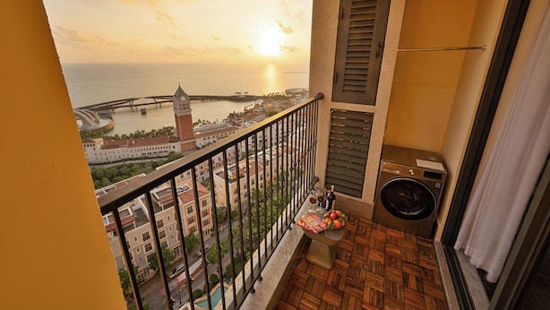 Un balcón con vistas a una ciudad costera, que incluye un puente y una torre del reloj, además de una lavadora.