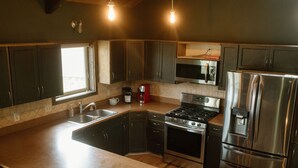 A modern kitchen with dark cabinets, stainless steel appliances, and a large island. - Entire home in Moscow, ID (Moscow)