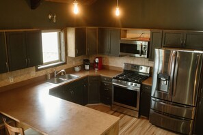 A modern kitchen with dark cabinets, stainless steel appliances, and a large island. - Entire home in Moscow, ID (Moscow)