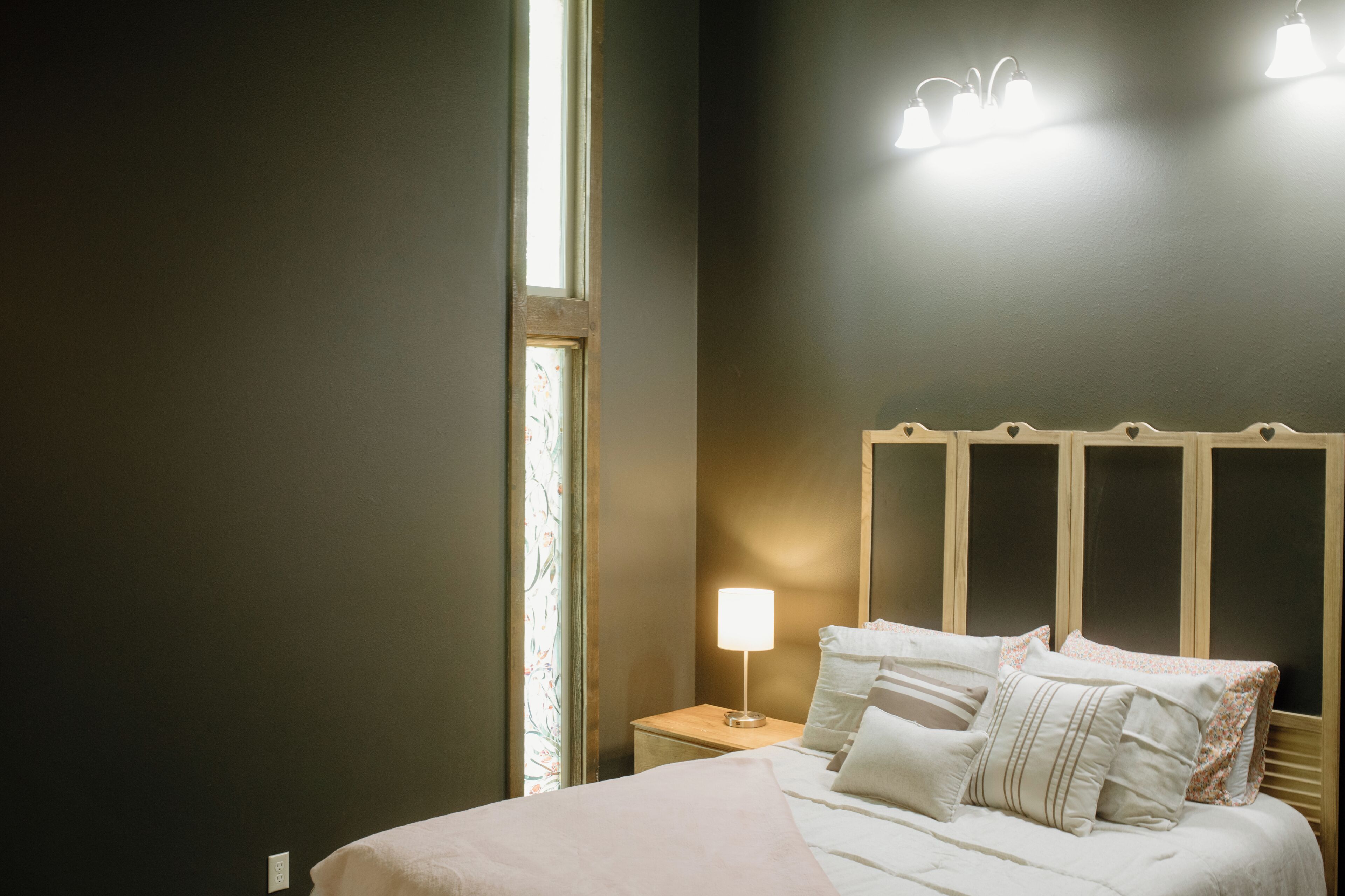 A bedroom with a bed, bedside lamp, and a window.