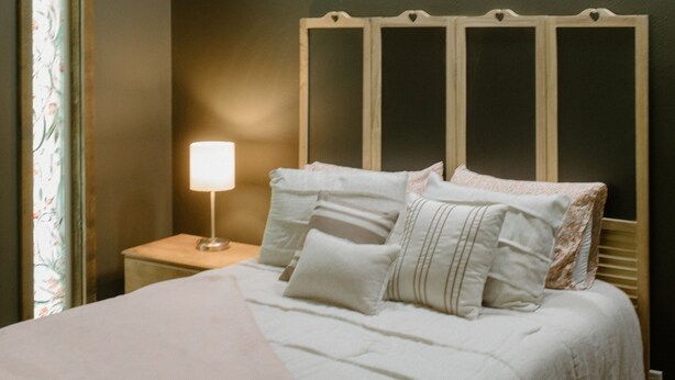 A bed with a wooden headboard, a bedside lamp, and a window with a view. - Entire home in Moscow, ID (Moscow)