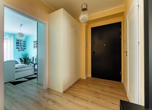 Ein modernes Interieur mit Holzboden, einer schwarzen Tür und einer Leuchte.