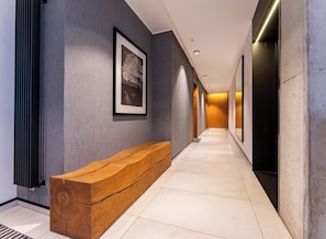 A modern hallway with a wooden bench, framed artwork, and a tiled floor. - Baltic Sea Coastal Apartment (Gdańsk)