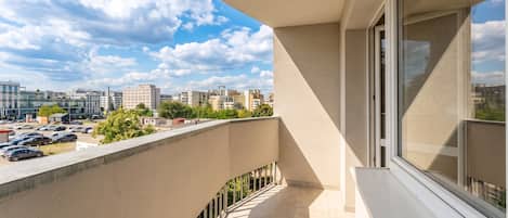 A balcony with a view of a parking lot and buildings in the distance.