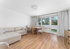 Uma sala moderna com um sofá, uma mesa de jantar de madeira e cadeiras.