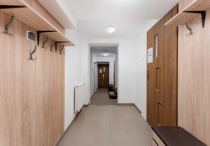 A hallway with lockers on both sides, a radiator, and a door at the end. - Woronicza Urban Studio #1 (Kraków)