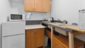 A compact kitchen with a microwave, coffee maker, sink, and wooden cabinets. - Woronicza Urban Studio #1 (Kraków)