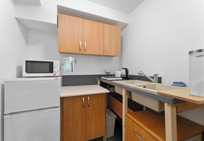 A compact kitchen with a microwave, coffee maker, sink, and wooden cabinets. - Woronicza Urban Studio #1 (Kraków)