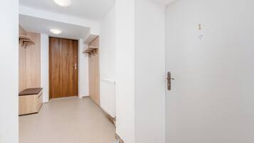 Un pasillo con una puerta de madera, un radiador y un banco.