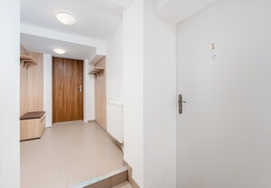 A hallway with a wooden door, a radiator, and a bench. - Woronicza Urban Studio #1 (Kraków)