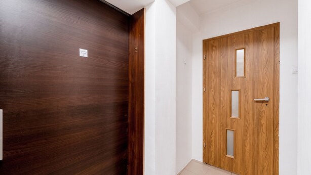 A hallway with two wooden doors, one with a label and the other with a handle and a keyhole. - Woronicza Urban Studio #1 (Kraków)