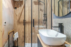 A modern bathroom with a freestanding bathtub, a glass shower enclosure, and a wooden vanity. - Słowackiego Chic Apartment (Katowice)