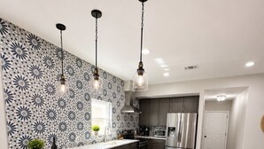 A modern kitchen with a central island, stainless steel appliances, and a patterned backsplash. - The Backyard Cantina Walk to Fair Park (Dallas)