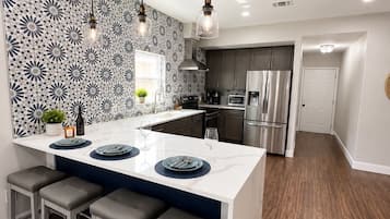 Una cocina moderna con una isla central, electrodomésticos de acero inoxidable y un salpicadero con diseño.