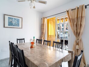A dining area with a marble table, black chairs, a ceiling fan, a framed picture, and a window with curtains. - Las Flores de Burriana 5 by Casasol by Interhome (Nerja)