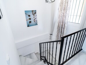 A staircase with a black railing, a white wall, and a framed picture of dandelions. - Las Flores de Burriana 5 by Casasol by Interhome (Nerja)