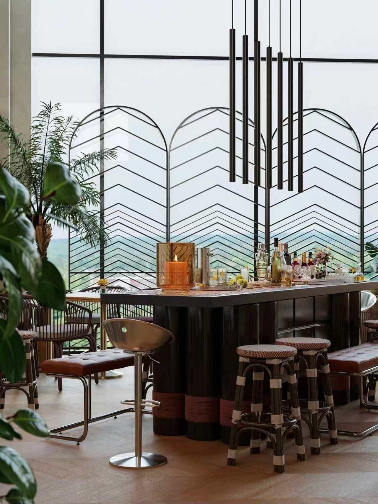 A bar area with a chevron-patterned backdrop, bar stools, and a variety of bottles and glasses on the counter.