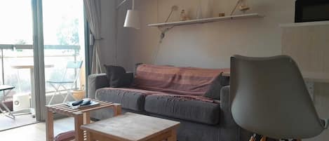 A modern living room with a sofa, a coffee table, a chair, and a TV on a stand.