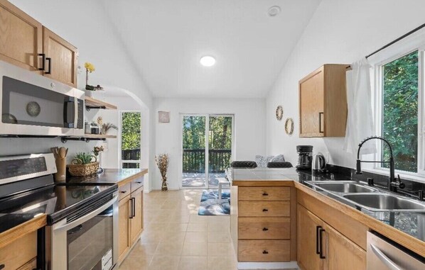 A modern kitchen with wooden cabinets, a black countertop, and stainless steel appliances.
