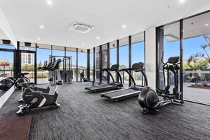 A gym with cardio machines, weight equipment, and large windows offering city views. - Beachside stay at Sandbar Burleigh Heads (Gold Coast)