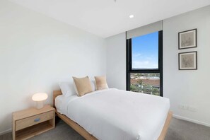 A bedroom with a bed, a nightstand, a window with a view, and two framed pictures on the wall. - Beachside stay at Sandbar Burleigh Heads (Gold Coast)