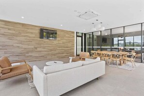 A modern interior with a wooden wall, a sofa, a dining area, and large windows. - Beachside stay at Sandbar Burleigh Heads (Gold Coast)