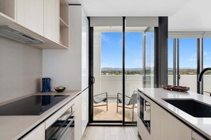 Eine moderne Küche mit einem großen Fenster, einer Schiebetür, die auf einen Balkon führt, und Blick auf die Landschaft.