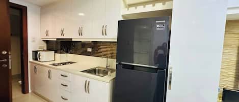 Une cuisine moderne avec des meubles blancs, un réfrigérateur noir et un pare-feu en carrelage.