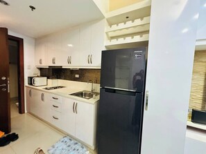 Una cocina moderna con armarios blancos, un refrigerador negro y un rebozadero de azulejos.
