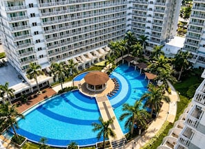 Un hotel con una piscina grande, varios balcones y palmeras.