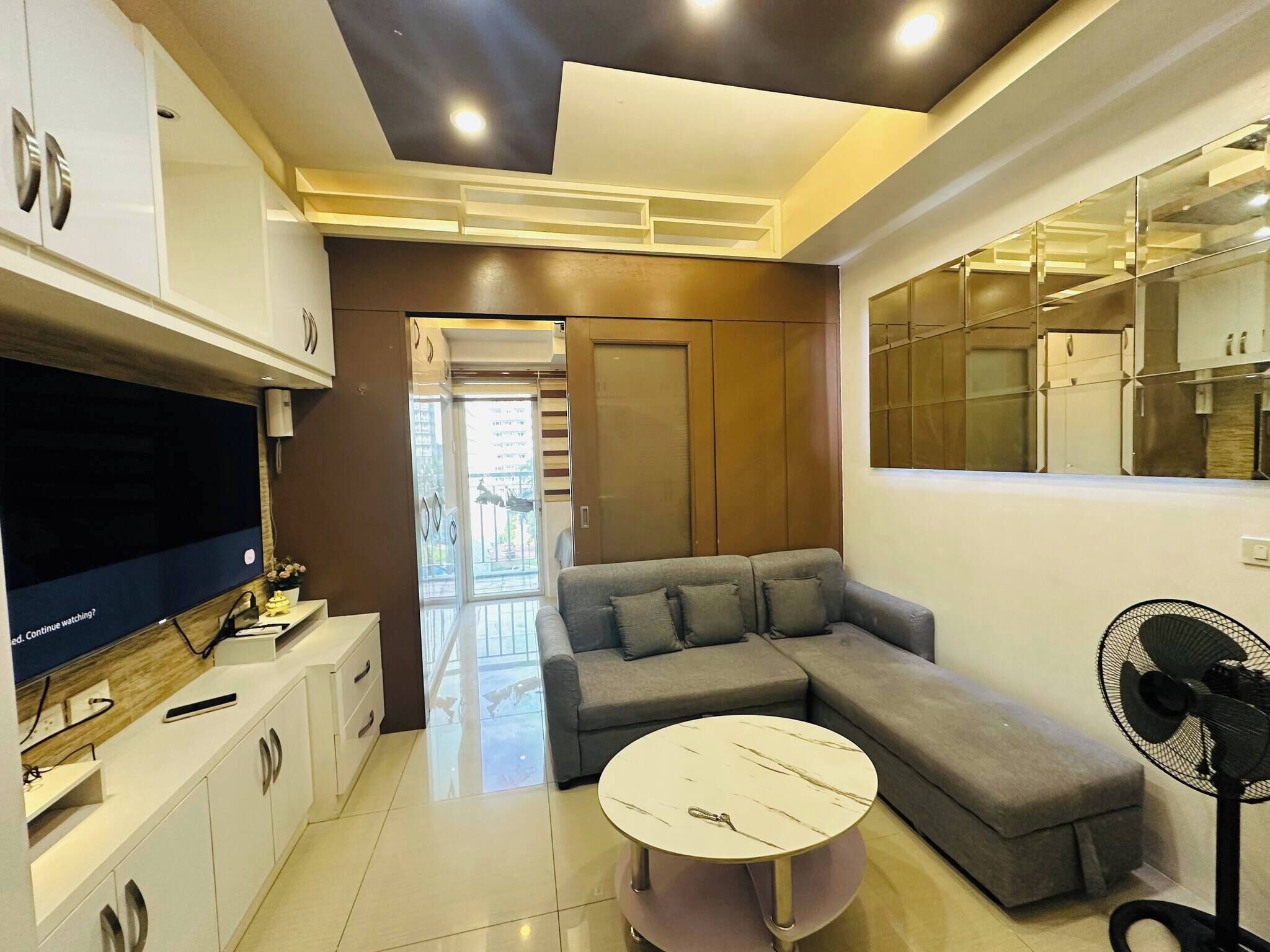 A modern living room with a sectional sofa, a round coffee table, and a flat-screen TV.