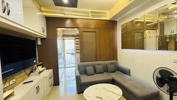 A modern living room with a sectional sofa, a round coffee table, and a flat-screen TV.