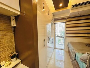 A bedroom with a bed, a wardrobe, a bathroom with a toilet, and a window with a view of buildings. - Wonderful Urban Retreat Modern Apartment in Pasay Front of Mall of Asia (Pasay)