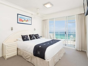 A hotel room with a bed, a nightstand, a window with a view of the sea, and a ceiling fan. - 2nd Avenue Apartments - 13B (2B/2B) (Gold Coast)