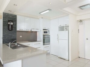 A modern kitchen with white cabinetry, a granite countertop, a built-in oven, and a refrigerator. - 2nd Avenue Apartments - 13B (2B/2B) (Gold Coast)