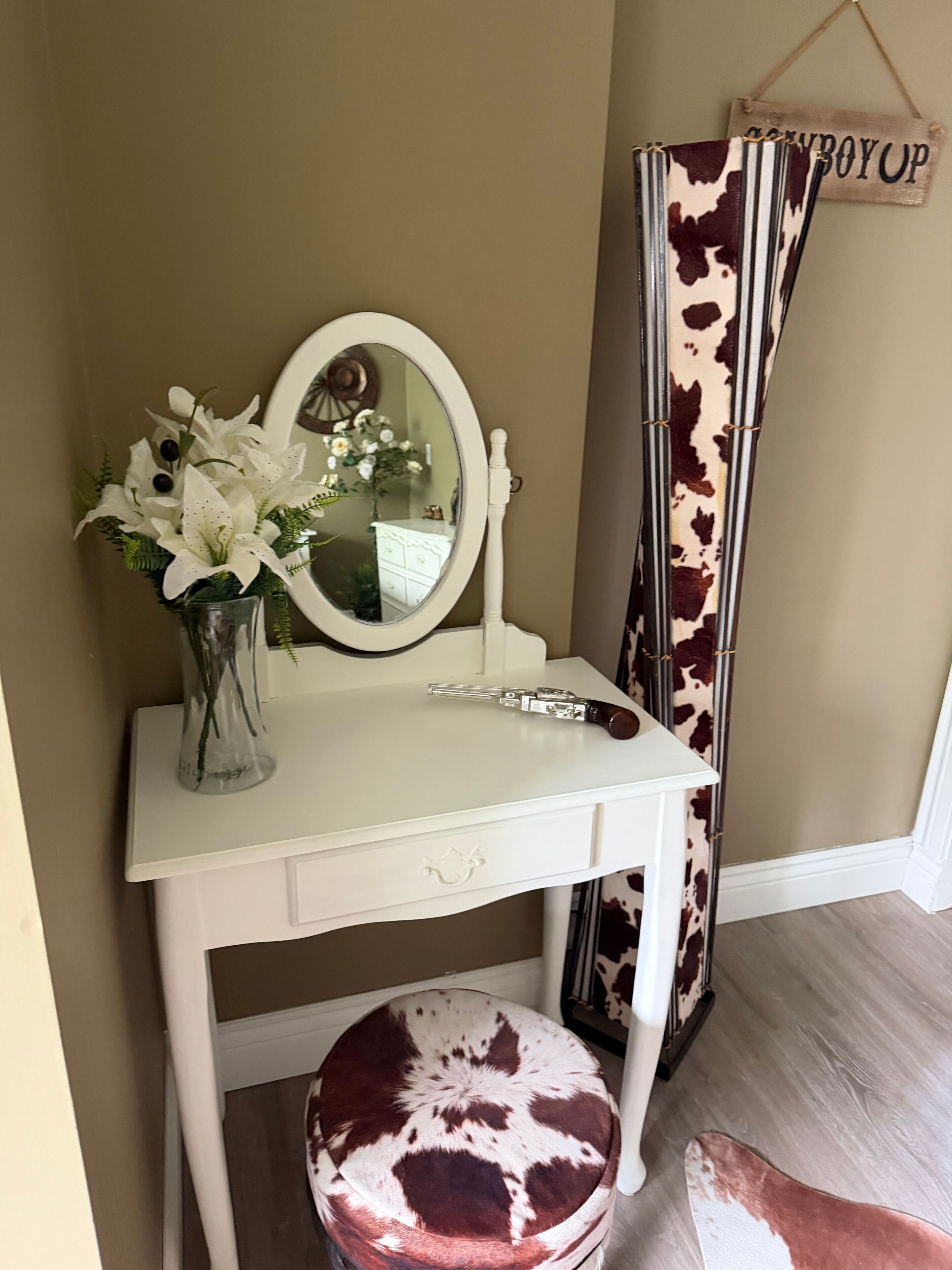 Une coiffeuse avec un miroir, un vase de fleurs et un pinceau à maquillage.