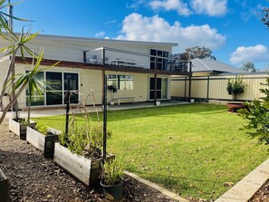 A residential property with a well-maintained lawn, a patio area, and a house with a large window and a balcony. - Peaceful country escape at Twin Tallows Guest House (Cowaramup)