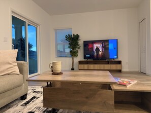 A modern living room with a sofa, coffee table, TV, and a plant.