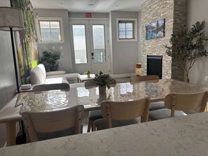 A modern dining area with a marble table, wooden chairs, and a fireplace. - Fox - Private Bedroom near Downtown and 17th Av (Calgary)