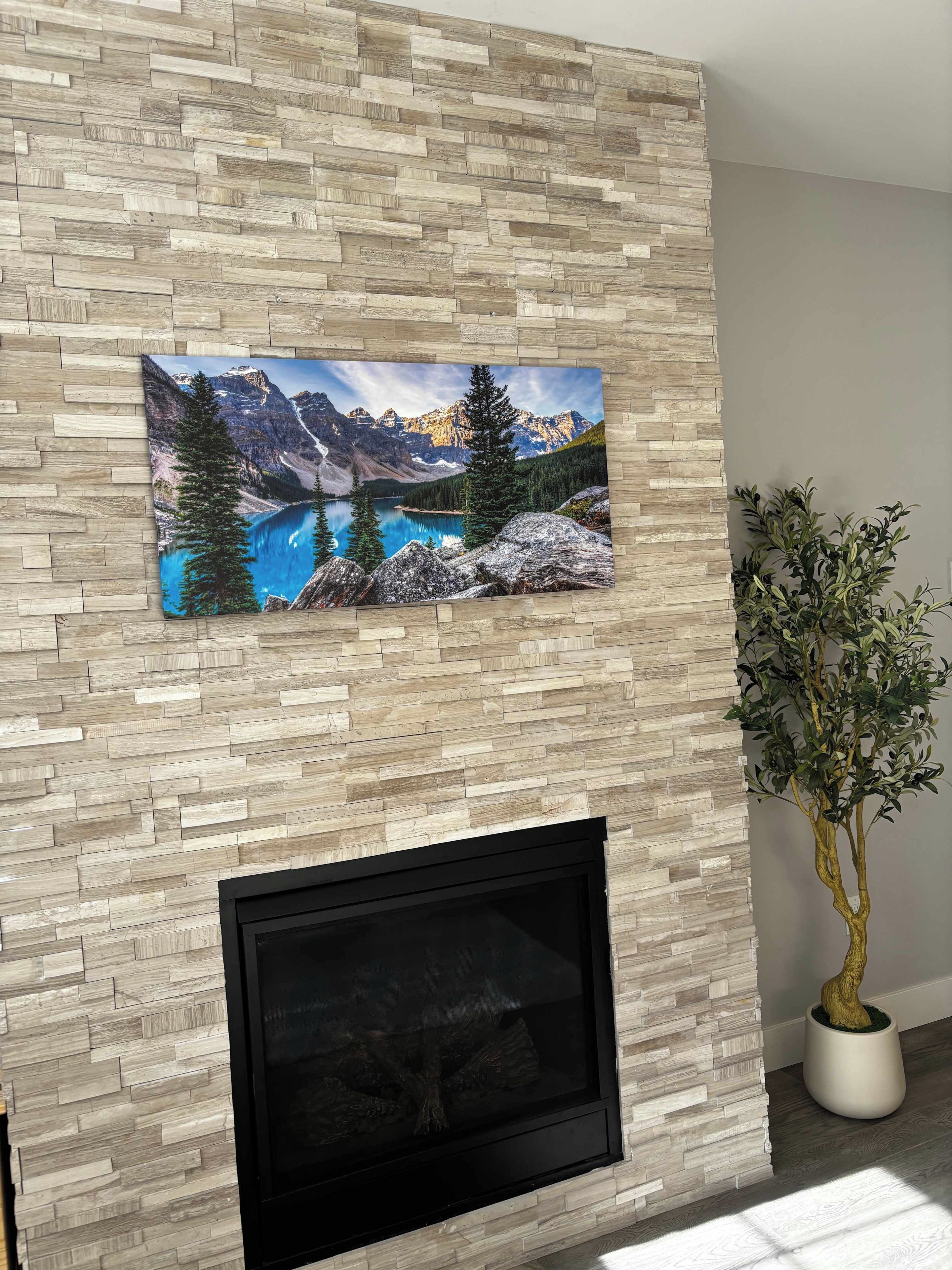 A fireplace with a framed landscape painting above it.
