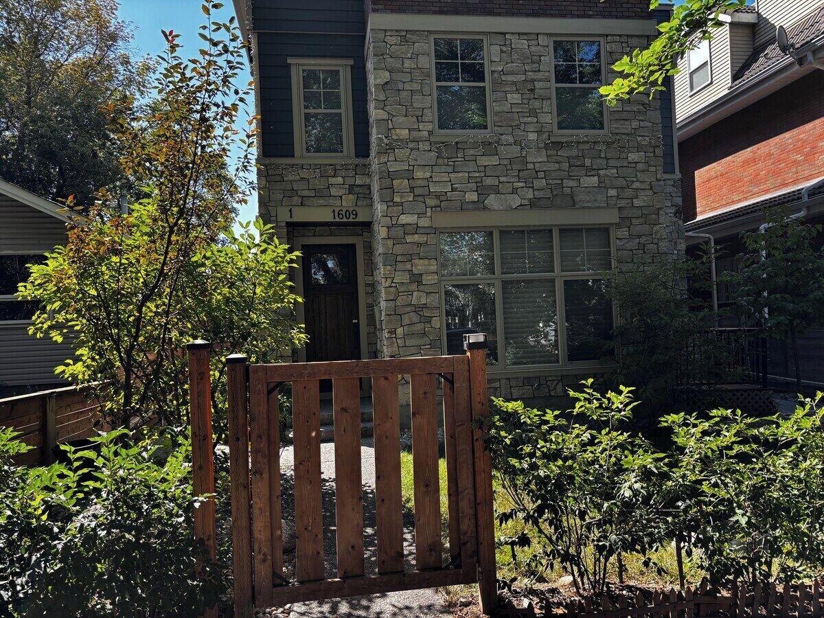 A stone house with a number '1609' on the door, surrounded by greenery.